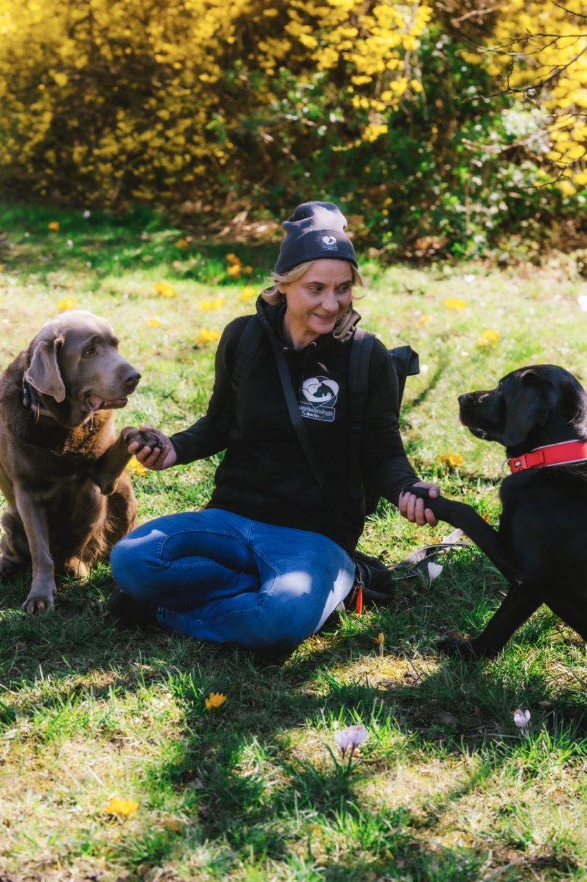 HeartcoredogsBerlin - Hundetraining - Mann sitzt mit seinem Hund im Park.